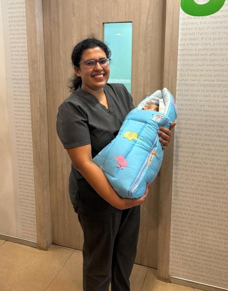 Dr. Anjani Dixit holding a newborn wrapped in a blue swaddle outside the ward