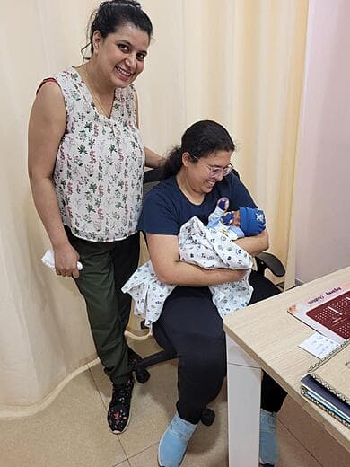 Dr. Anjani Dixit holding a newborn while the mother stands beside her