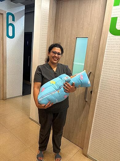 Dr. Anjani Dixit carrying a newborn in a blue swaddle at the ward door