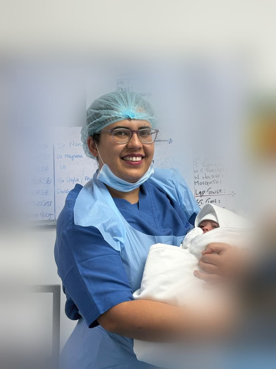 Dr. Anjani Dixit in theatre scrubs holding a newborn after a delivery