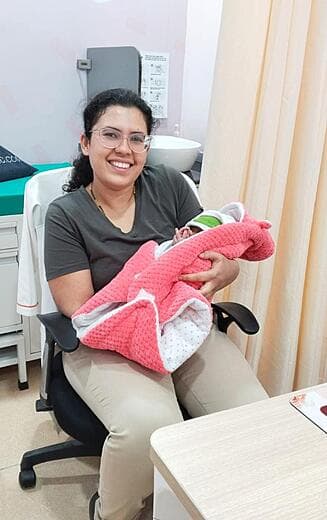 Dr. Anjani Dixit in her consulting room with a newborn wrapped in a pink blanket