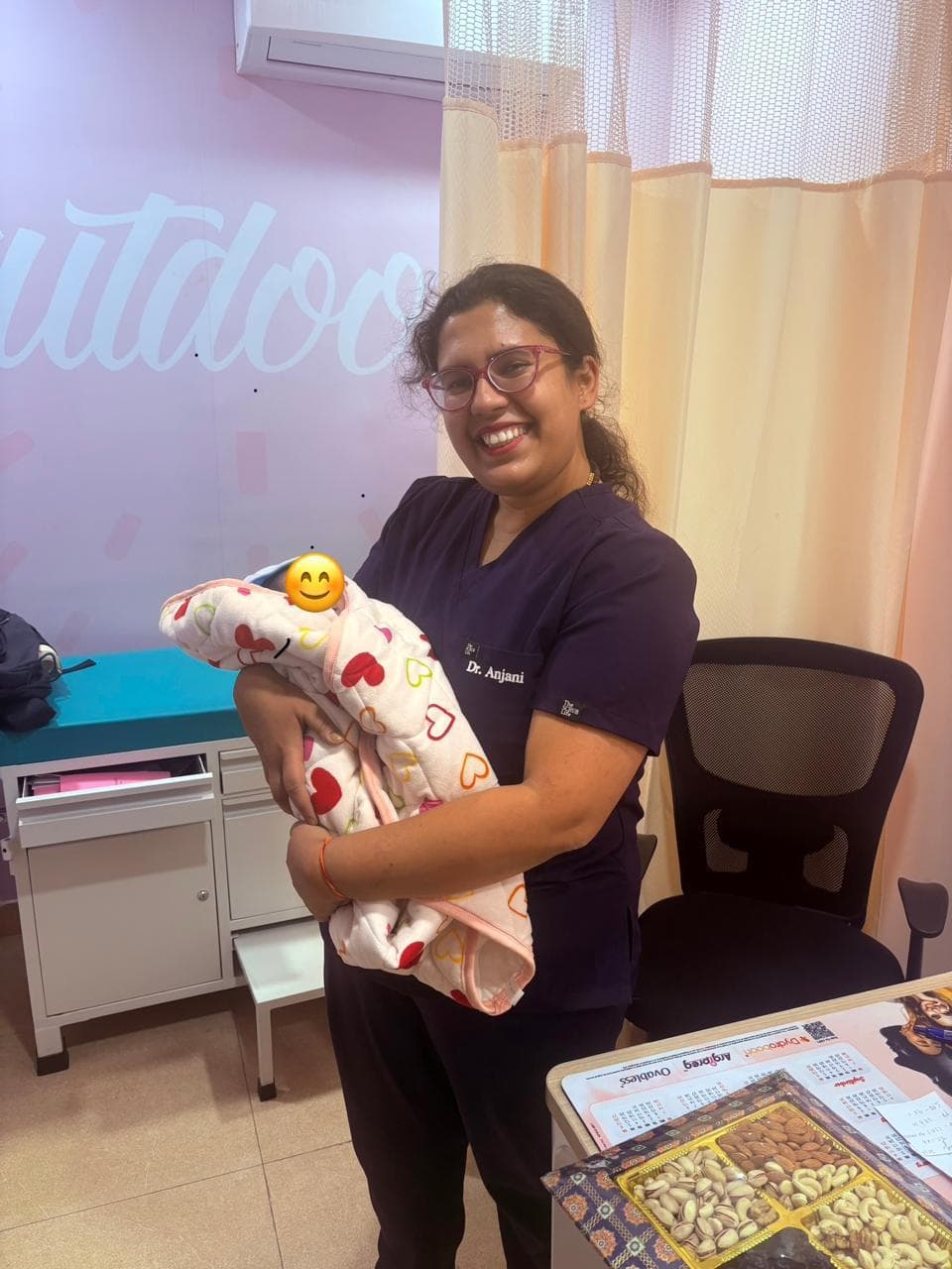 Dr. Anjani Dixit holding a newborn in a printed blanket in her consulting room