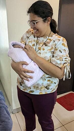 Dr. Anjani Dixit carrying a newborn wrapped in a pink blanket at the clinic
